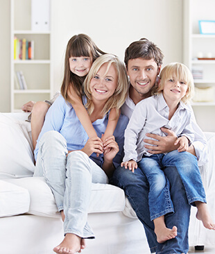 family of four is sitting on a couch