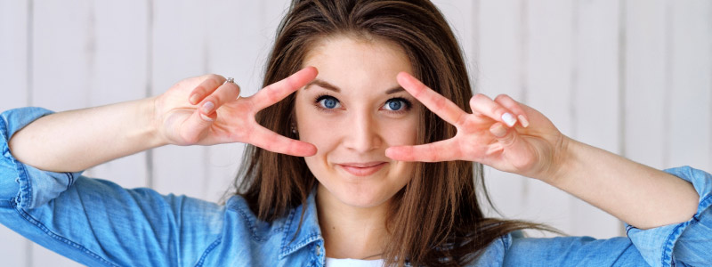 brunette woman making peace signs around her face