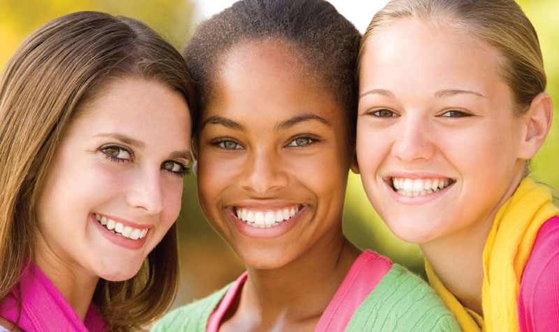 Closeup of 3 teenage girls around the age of when their wisdom teeth erupt