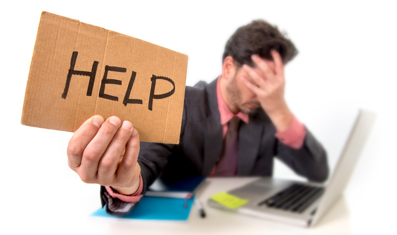 Brunette man with nighttime teeth grinding holds a HELP sign and puts his head in his hand