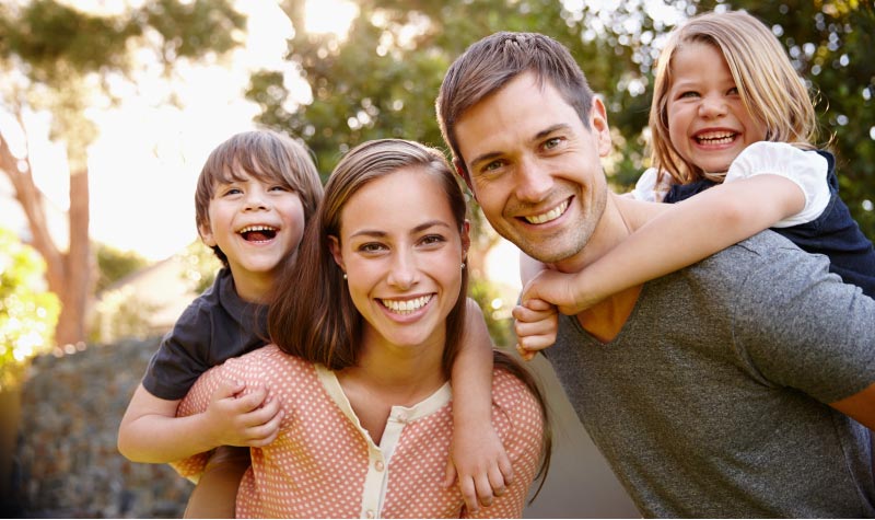 young family of four piggyback rides