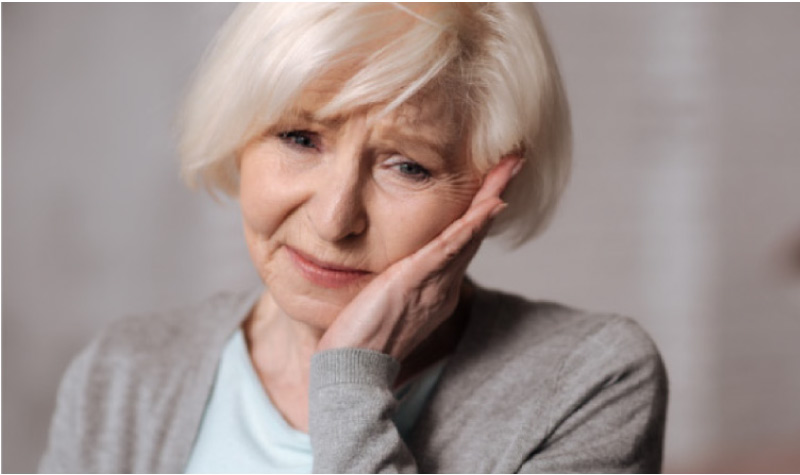 senior woman holding her jaw in pain from a damaged tooth