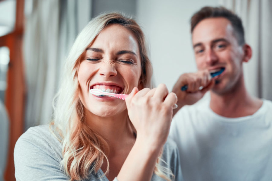 Woman and man brushing their teeth for optimal oral hygiene