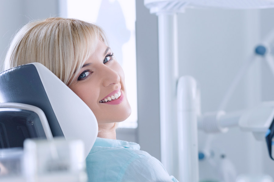 Blonde woman smiling from the dental chair after a preventive care exam.