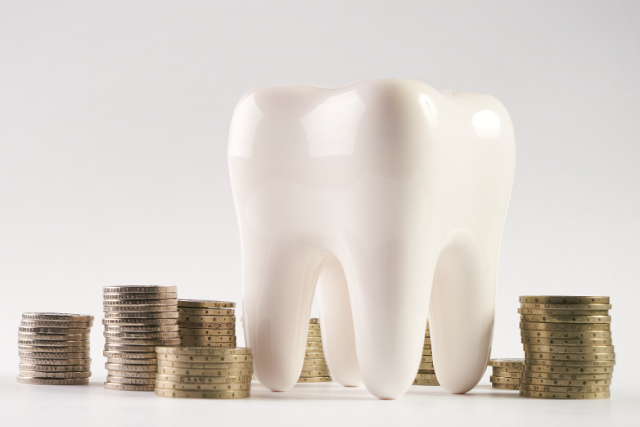 Model of a tooth next to a pile of coins.