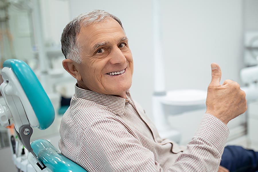 Senior gentleman gives a thumbs up from the dental chair.