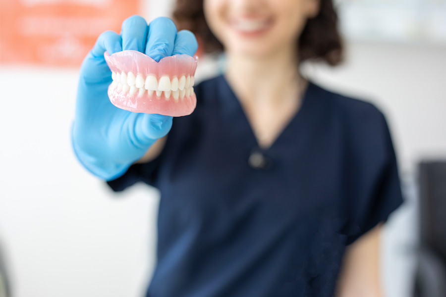 denture care, photo of woman holding dentures, dentures, prosthetic teeth, missing teeth